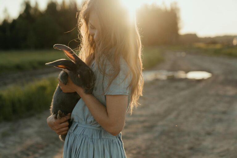 woman in blue dress holding black and brown short coated dog